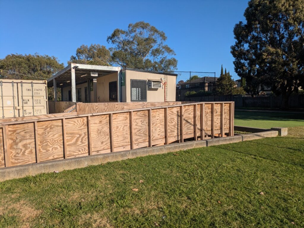 Temporary rooms beside a storage container, with a covered entrance and timber access ramp.