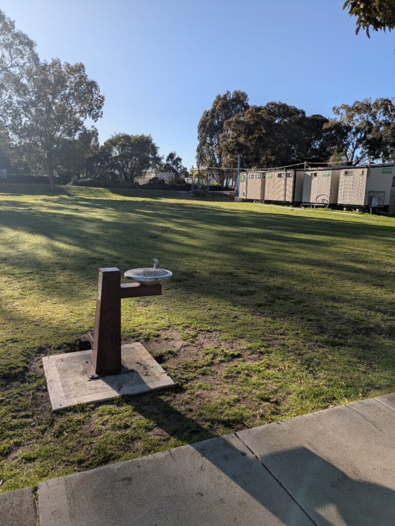 Row of portable toilet and shower units beside the grassed area at Mackie Reserve.